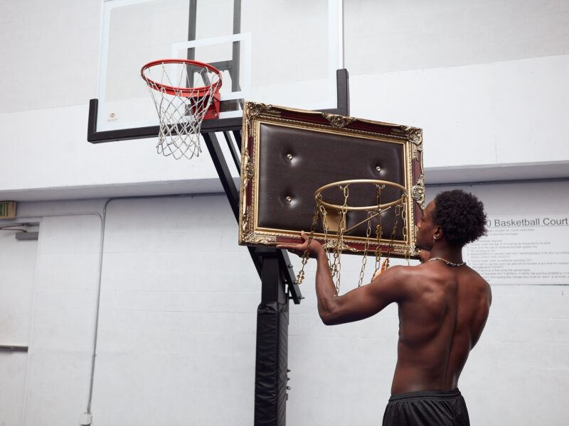 A man holding a custom luxury basketball hoop in front of a modern basketball hoop