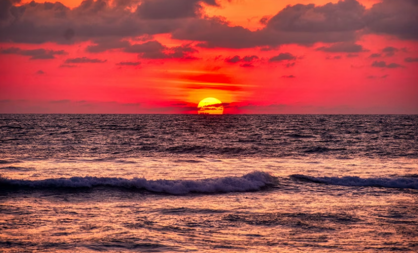 A golden sun setting over a serene beach.